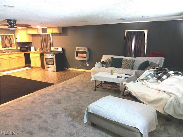 living room featuring sink, heating unit, light hardwood / wood-style flooring, a textured ceiling, and ceiling fan