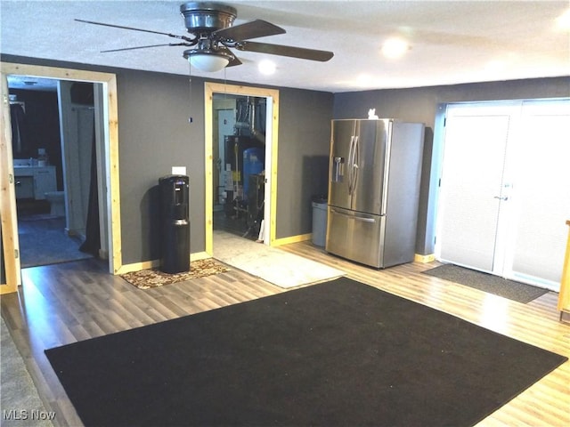 kitchen with hardwood / wood-style flooring, ceiling fan, stainless steel fridge with ice dispenser, and water heater