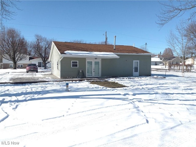 snow covered rear of property featuring french doors