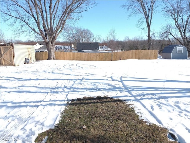 yard layered in snow with a storage shed