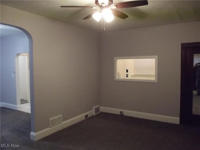 spare room with ceiling fan and dark colored carpet