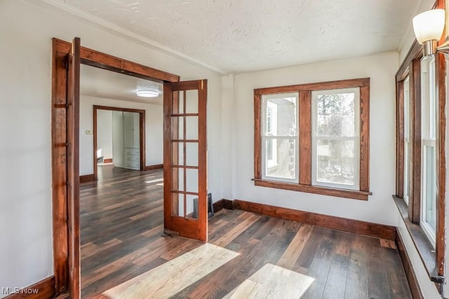 spare room with french doors, dark hardwood / wood-style floors, and a textured ceiling