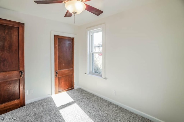 empty room with plenty of natural light, carpet floors, and ceiling fan