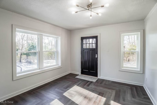 foyer entrance featuring a notable chandelier, dark parquet flooring, and a textured ceiling