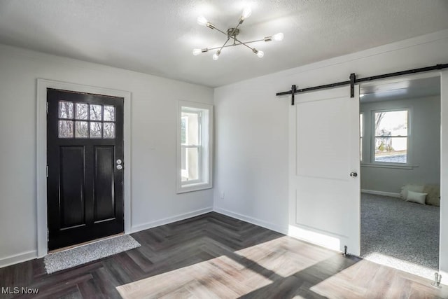 entrance foyer featuring dark parquet flooring, a barn door, and a chandelier