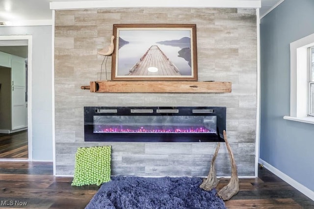 interior details featuring a tiled fireplace, ornamental molding, and wood-type flooring