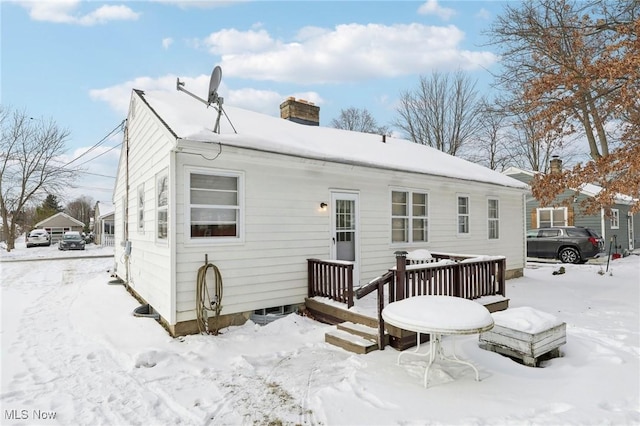 snow covered back of property featuring a wooden deck