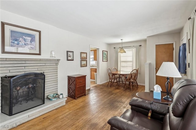 living room with a brick fireplace and hardwood / wood-style floors