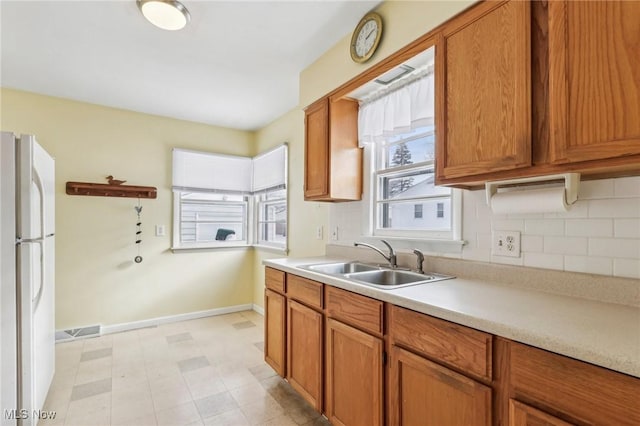 kitchen featuring white refrigerator, sink, and backsplash