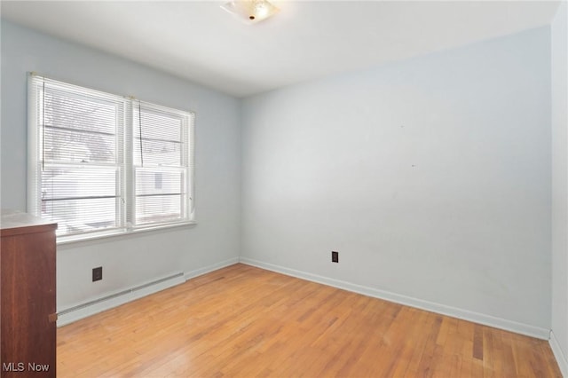 spare room with light wood-type flooring, a baseboard radiator, and plenty of natural light