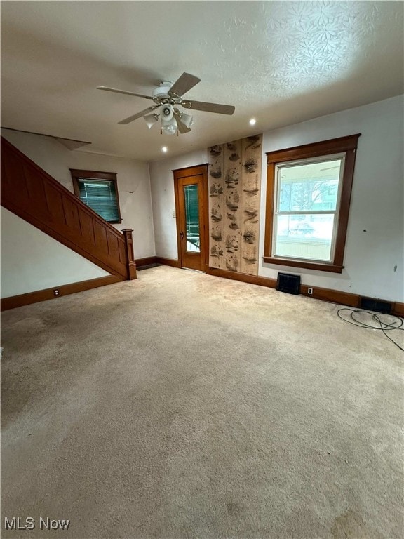 unfurnished living room featuring ceiling fan, carpet floors, and a textured ceiling