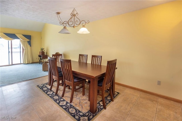 dining area with vaulted ceiling, a textured ceiling, and light tile patterned flooring