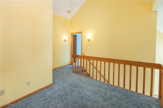 hallway featuring high vaulted ceiling and dark carpet