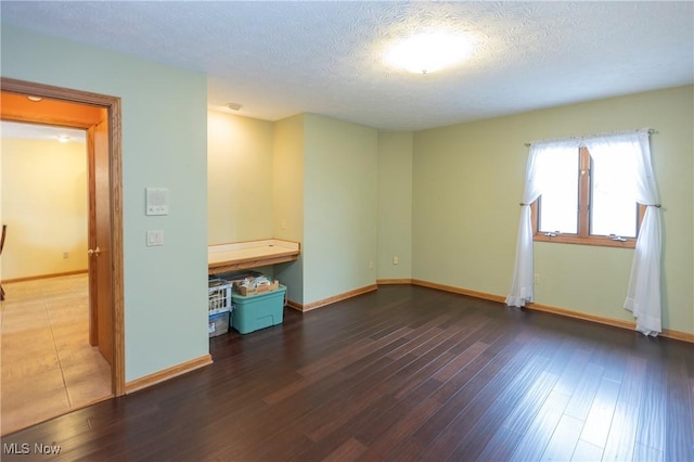 spare room with dark hardwood / wood-style floors and a textured ceiling