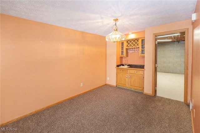 carpeted empty room with wet bar and a textured ceiling