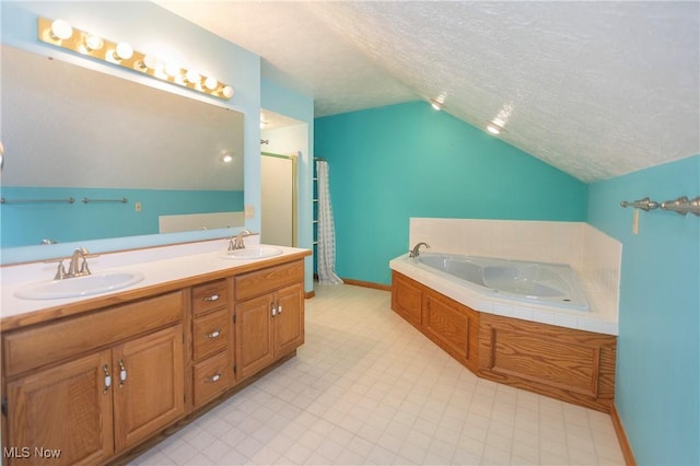 bathroom featuring vanity, vaulted ceiling, a tub, and a textured ceiling