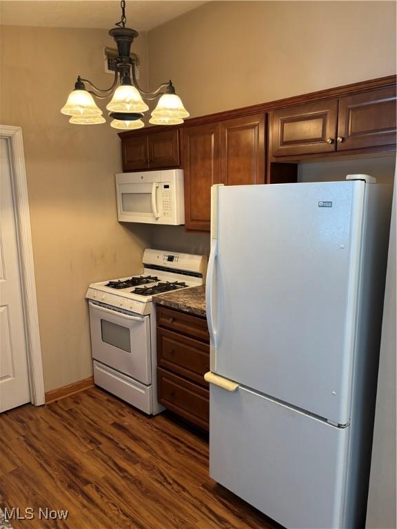 kitchen with dark hardwood / wood-style flooring, pendant lighting, and white appliances