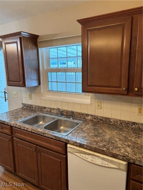 kitchen featuring hardwood / wood-style floors, tasteful backsplash, dishwasher, sink, and a textured ceiling