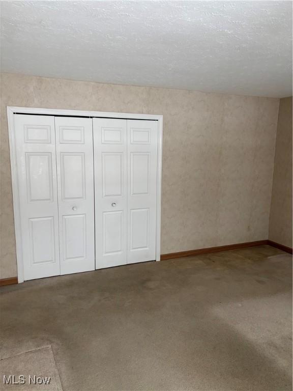 unfurnished bedroom with carpet flooring, a textured ceiling, and a closet