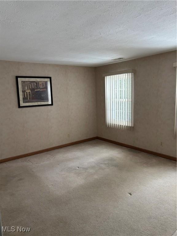 carpeted empty room featuring a textured ceiling