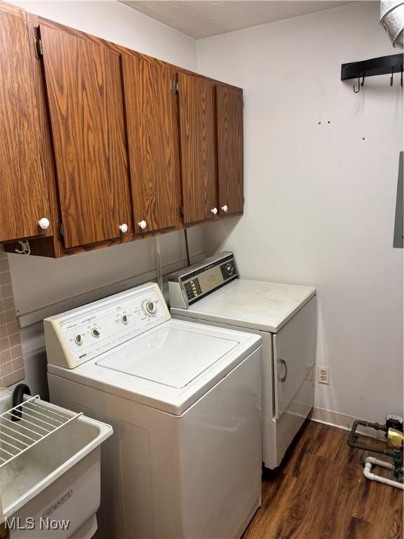 clothes washing area with cabinets, dark hardwood / wood-style floors, washer and clothes dryer, and sink