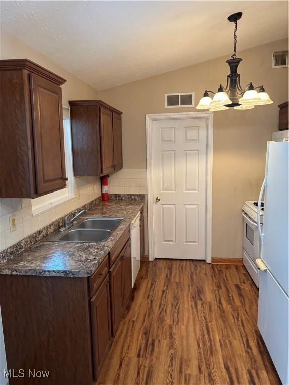 kitchen with vaulted ceiling, tasteful backsplash, sink, dark hardwood / wood-style flooring, and white appliances