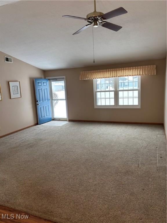 carpeted spare room featuring ceiling fan, lofted ceiling, and plenty of natural light