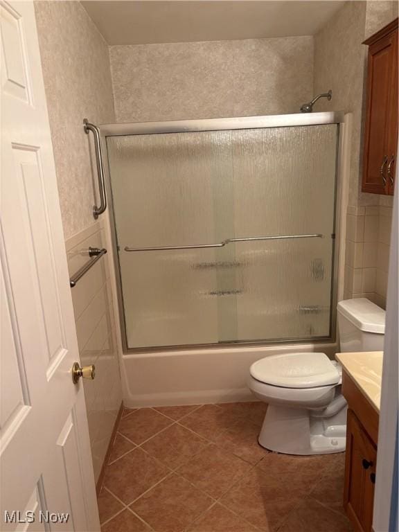 full bathroom with tile patterned flooring, enclosed tub / shower combo, vanity, and toilet