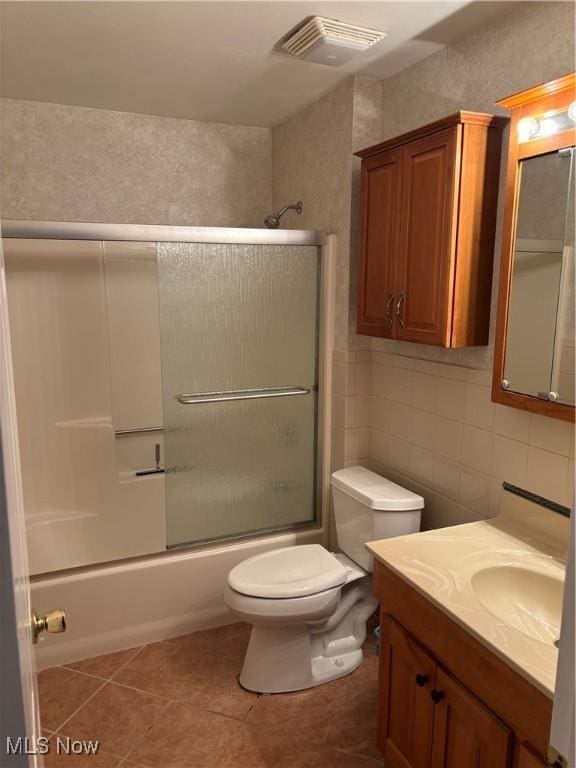 full bathroom with toilet, bath / shower combo with glass door, vanity, tile patterned flooring, and decorative backsplash