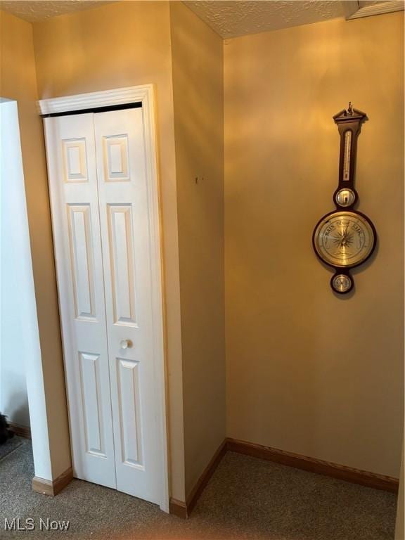 hall with carpet flooring and a textured ceiling