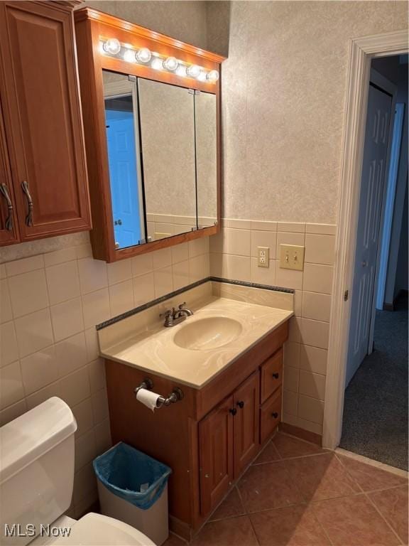 bathroom featuring vanity, tile patterned floors, tile walls, and toilet