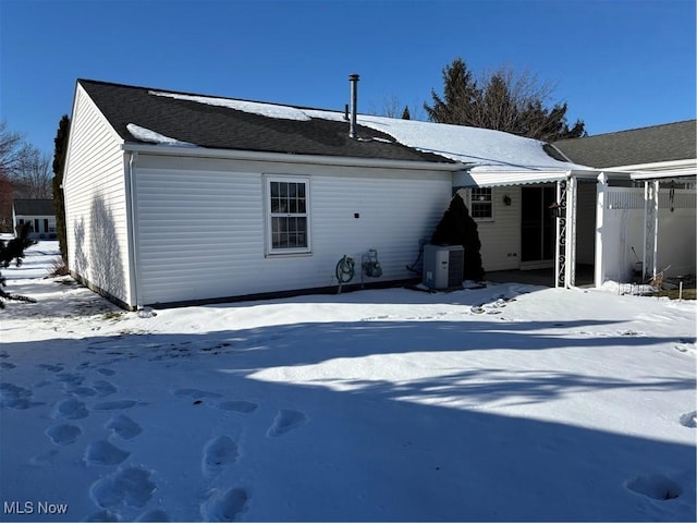 snow covered back of property featuring central AC unit