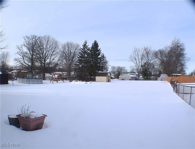 yard covered in snow featuring a storage shed