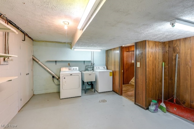 basement featuring sink, wooden walls, and washing machine and dryer