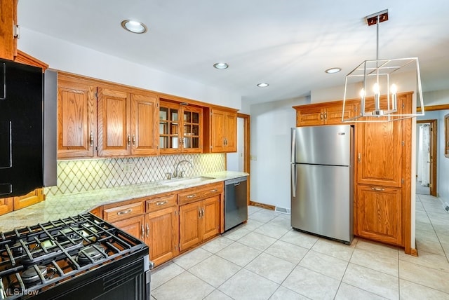 kitchen with tasteful backsplash, sink, hanging light fixtures, stainless steel appliances, and light stone countertops