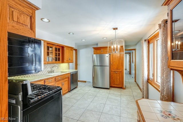 kitchen featuring sink, hanging light fixtures, appliances with stainless steel finishes, tile counters, and backsplash