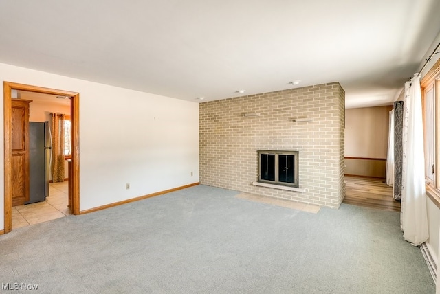 unfurnished living room featuring a brick fireplace and light colored carpet