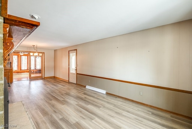 empty room featuring an inviting chandelier and light hardwood / wood-style floors