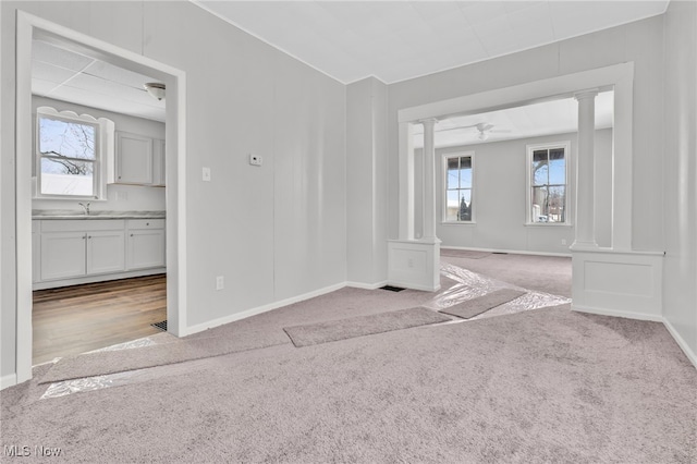 unfurnished room with light carpet, sink, and decorative columns