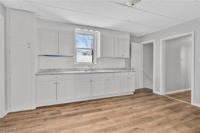 kitchen with a paneled ceiling, light hardwood / wood-style flooring, and white cabinets