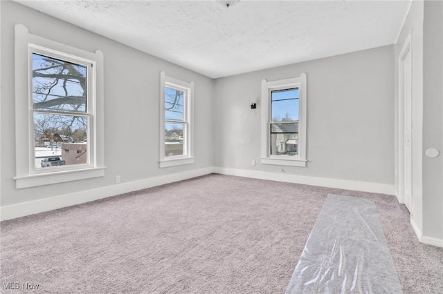 carpeted spare room featuring plenty of natural light and a textured ceiling