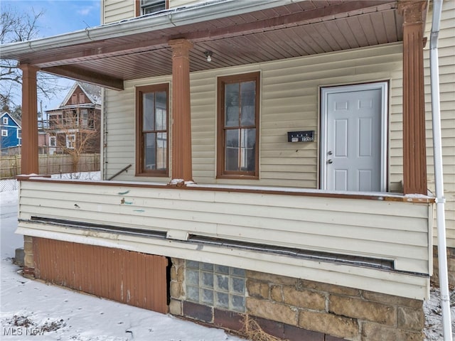 snow covered property entrance featuring a porch