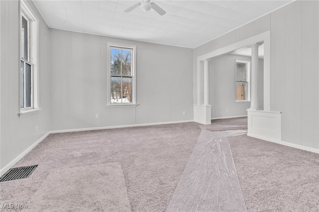 spare room featuring carpet, ceiling fan, and ornate columns