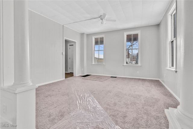 carpeted spare room with ornate columns and ceiling fan