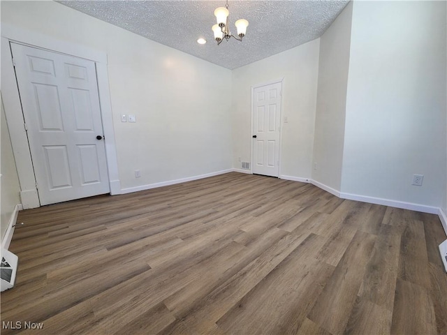 unfurnished room featuring hardwood / wood-style floors, a notable chandelier, and a textured ceiling