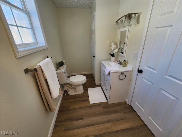 bathroom with vanity, wood-type flooring, toilet, and a textured ceiling