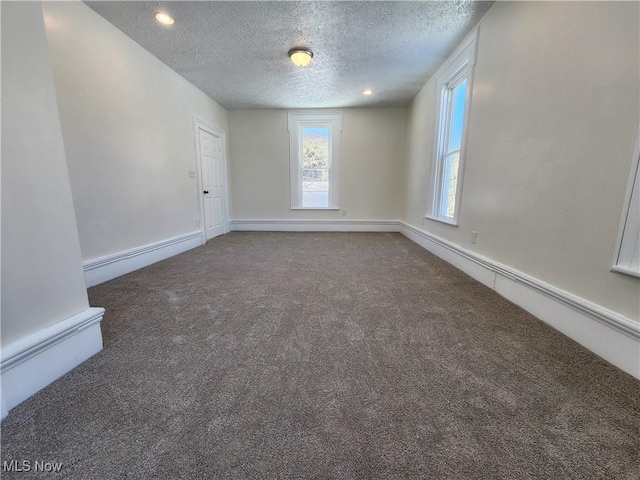 carpeted empty room with a baseboard heating unit and a textured ceiling