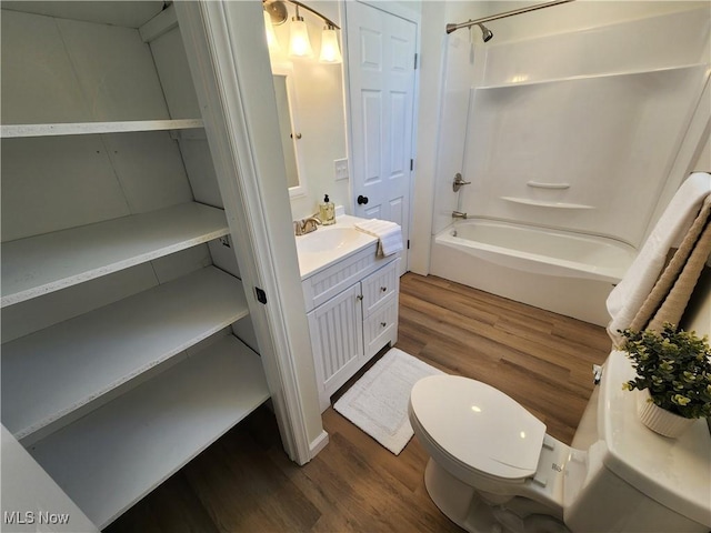 full bathroom featuring vanity, wood-type flooring, shower / bathtub combination, and toilet