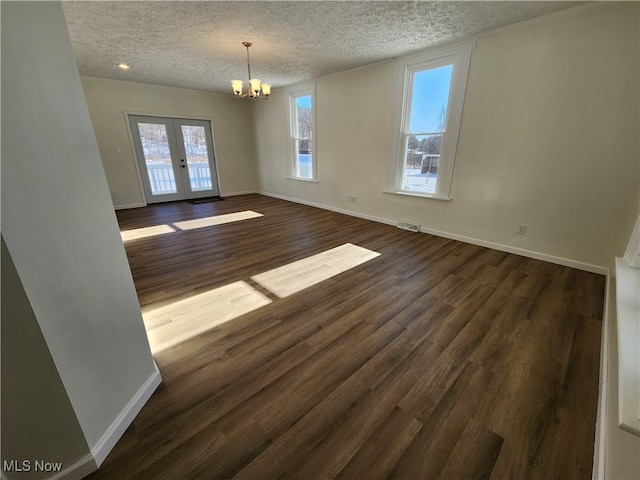 interior space featuring dark wood-type flooring, a textured ceiling, french doors, and a notable chandelier