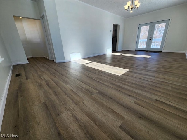 spare room with an inviting chandelier, dark hardwood / wood-style flooring, a textured ceiling, and french doors